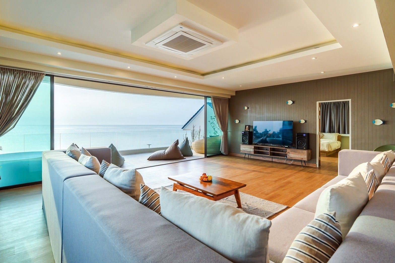 Spacious living room with ocean view at All About VII Pool Villa, near Bangket Beach, Cha Am. Large sofa and TV.