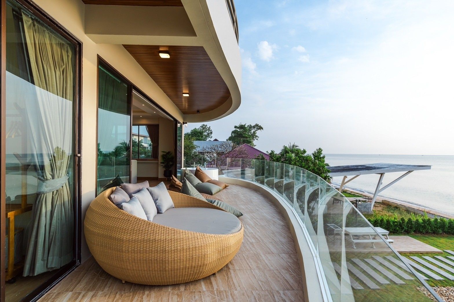 Outdoor terrace at All About VII Pool Villa near Bangket Beach, Cha-am. Features a round wicker sofa and ocean view.