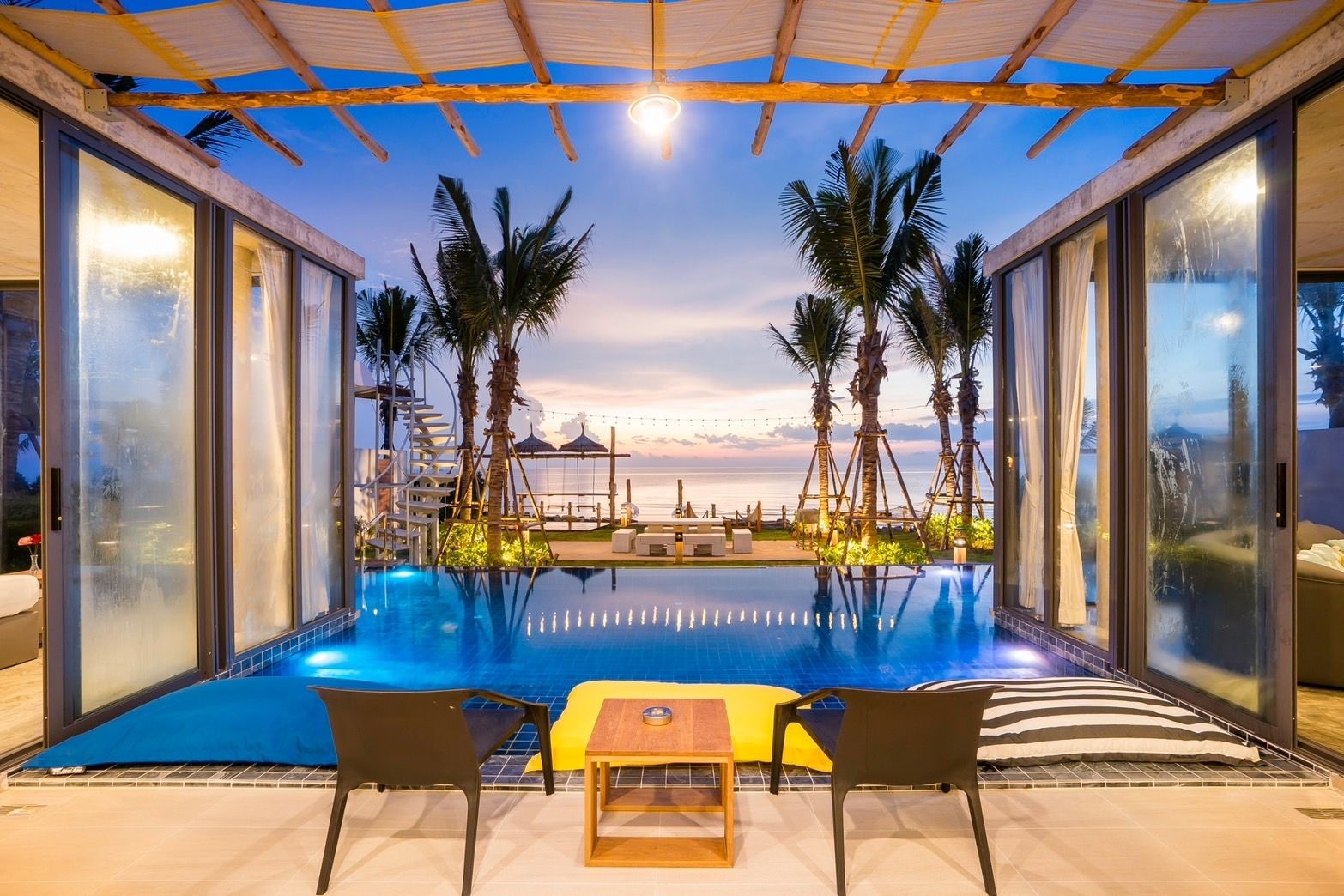 Amore' A Pool Villa beachfront infinity pool view at dusk, หาดปึกเตียน-ชะอำ. Palm trees and ocean view from the pool deck.