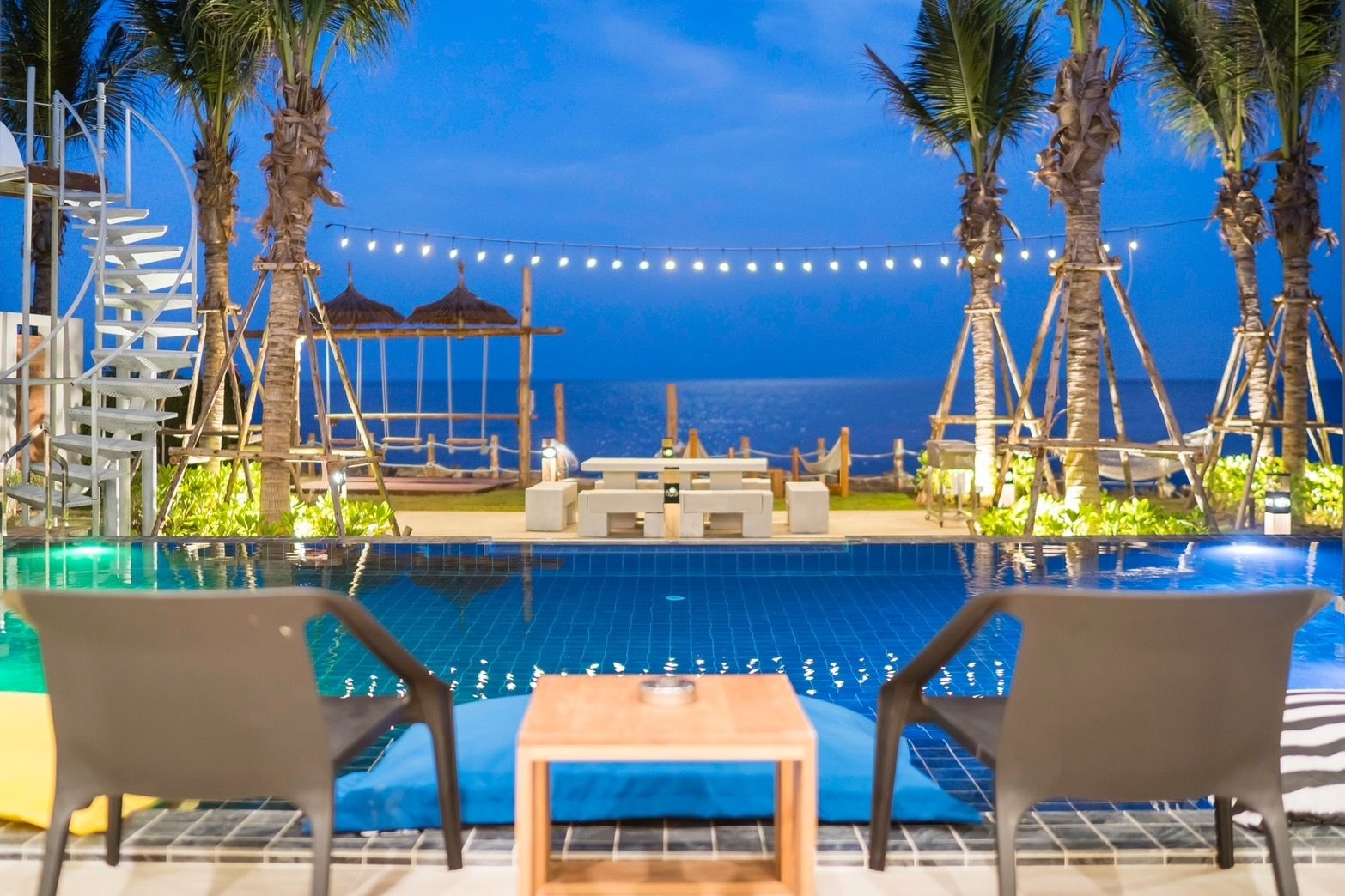 Amore' A Pool Villa poolside view at dusk in หาดปึกเตียน-ชะอำ. Lounge chairs and ocean view.