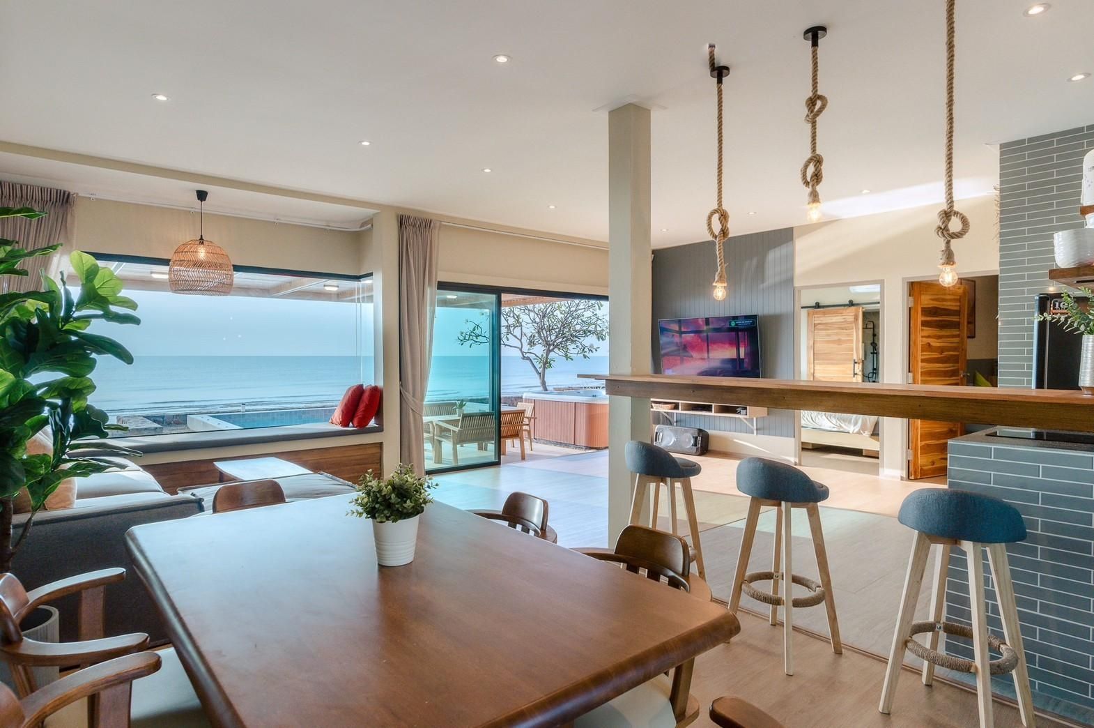Open-plan living and dining area at Beach Blanca IV pool villa, Cha-Am. Ocean view, bar stools, and dining table.