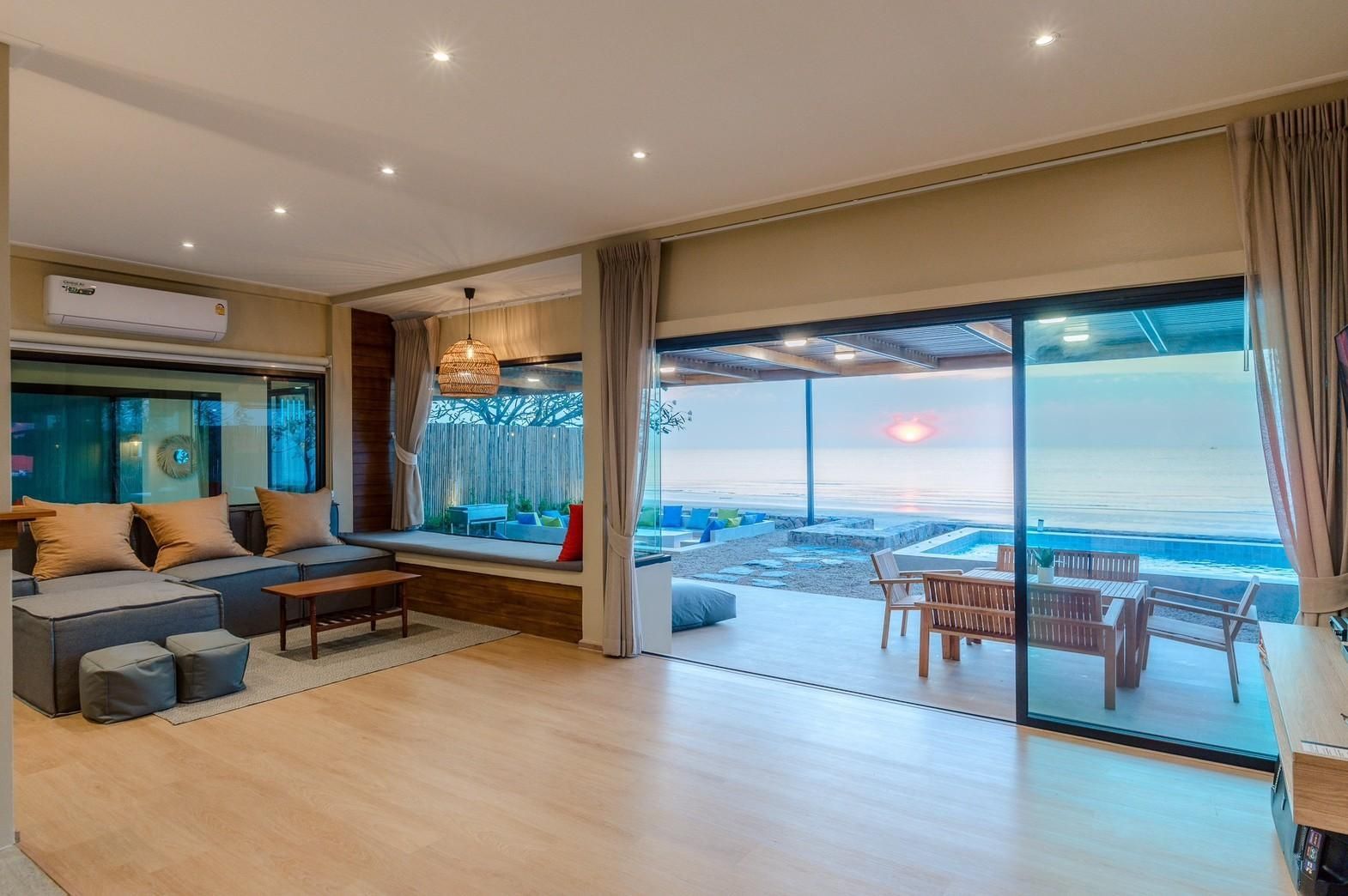 Living room with ocean view at Beach Blanca IV Pool Villa, Cha-Am. Sofa, cushions, and outdoor dining visible.