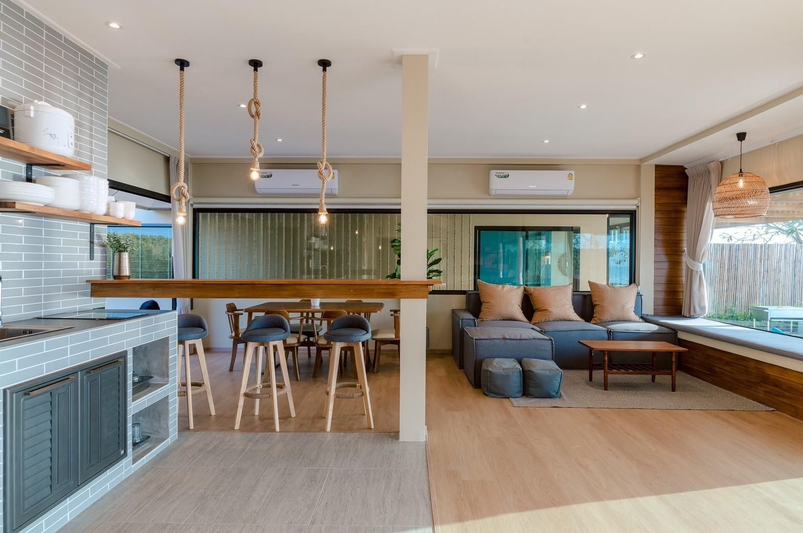 Open-plan living and dining area at Beach Blanca IV Pool Villa, Cha-Am. Features kitchen bar, dining table, and comfortable s