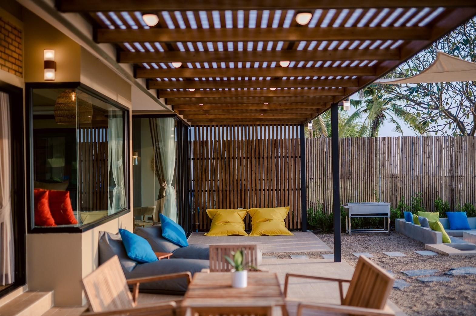 Outdoor patio with beanbag chairs at Beach Blanca IV Pool Villa, Cha-Am. Covered seating area with bamboo fence.
