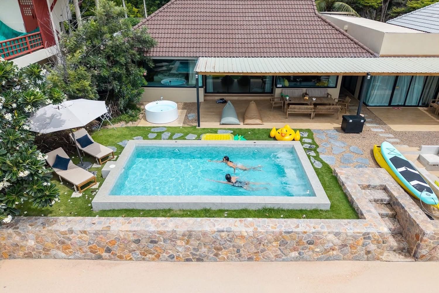 Aerial view of Beach Blanca IV pool villa in Cha-Am, Thailand. People swimming in the pool, jacuzzi, and outdoor seating visi