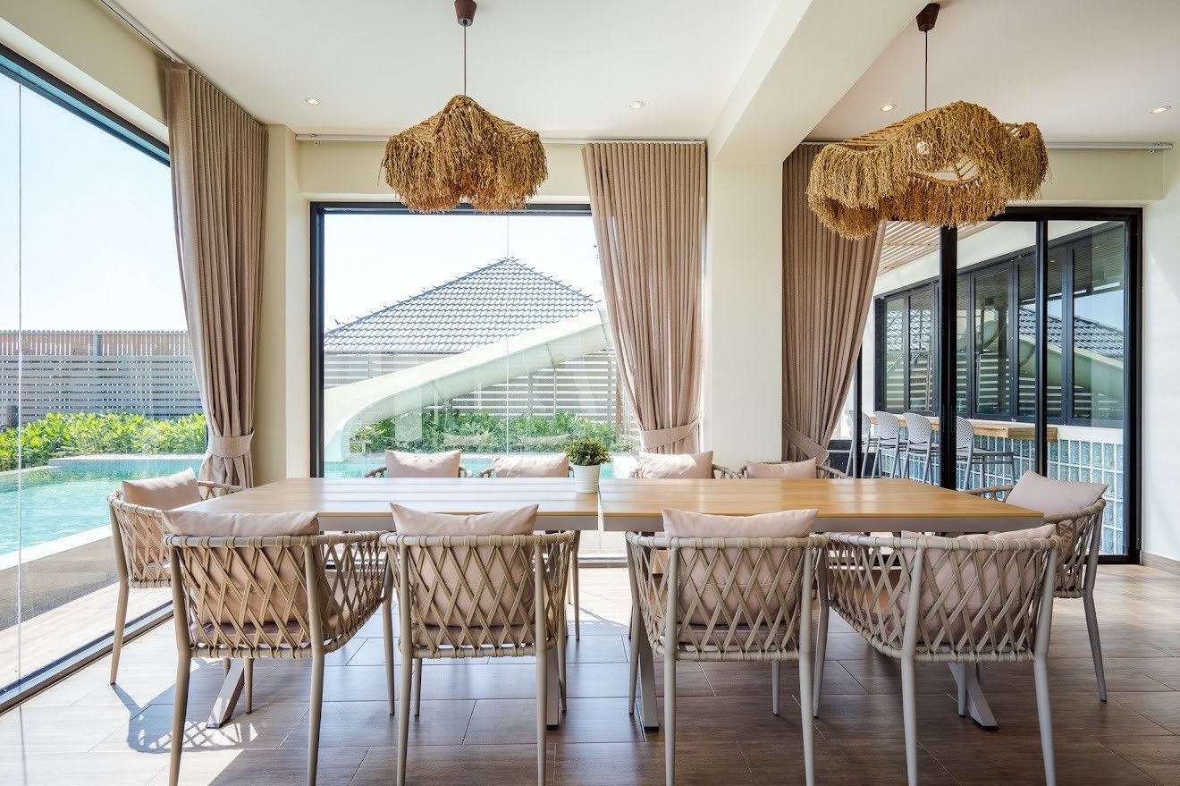 Indoor dining table at Beach Mood VI Pool Villa, Cha Am. View of pool and water slide through large windows.