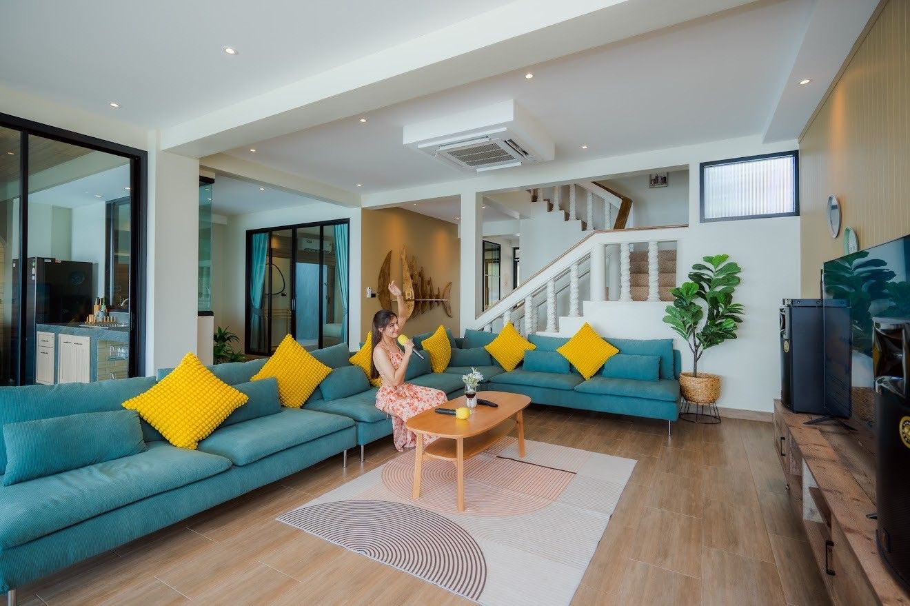 Beach Mood VI Pool Villa living room in หาดบางเกตุ ชะอำ with karaoke setup and large blue sofa with yellow pillows.