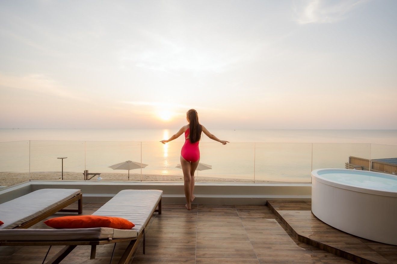 Ocean view terrace at Beach Mood VI Pool Villa, Cha Am. Woman in swimsuit enjoys the sunrise from the jacuzzi.