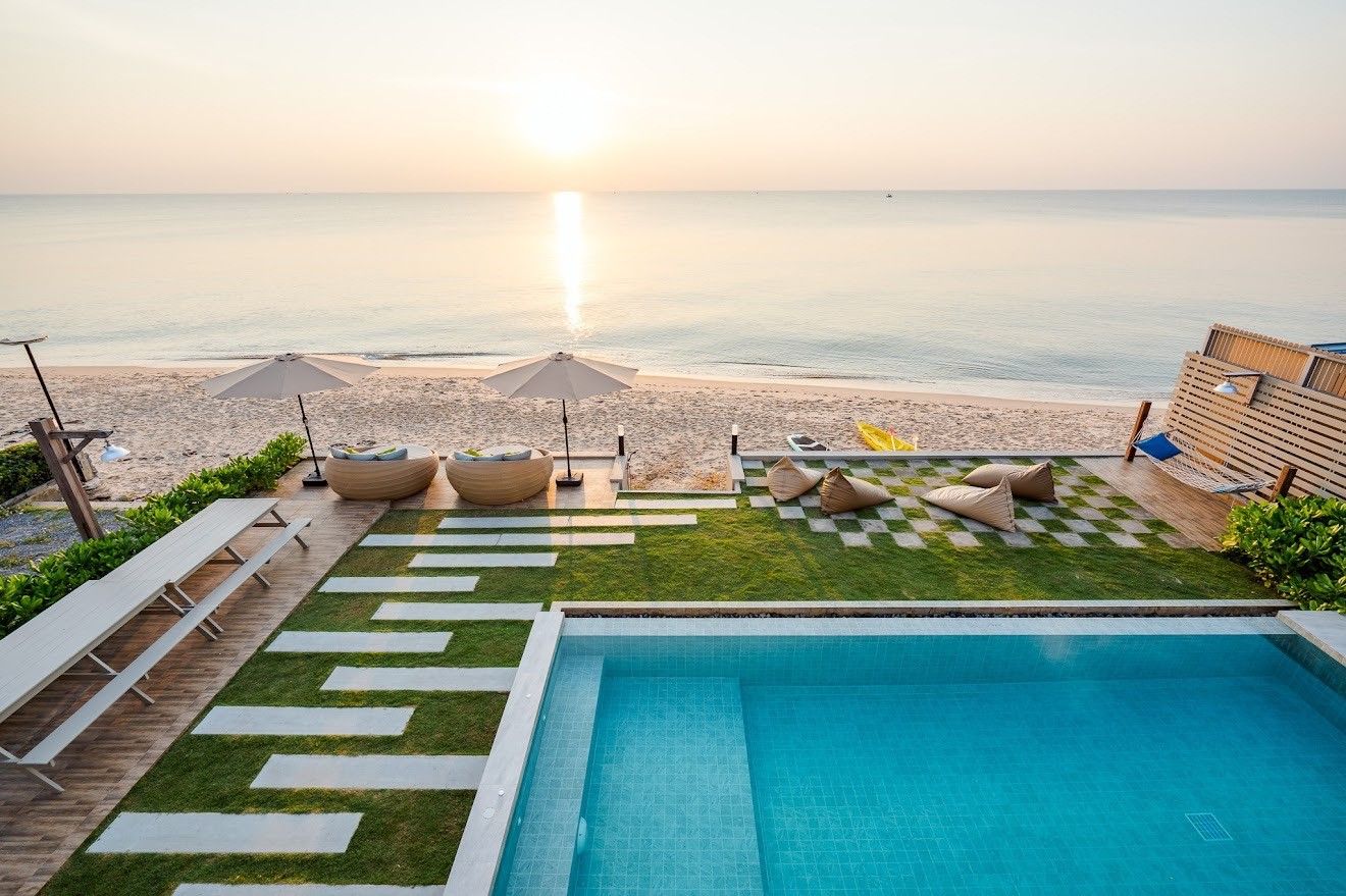 Beach Mood VI pool villa, หาดบางเกตุ ชะอำ. Aerial view of pool, beach access, lounge chairs, and bean bags at sunrise.
