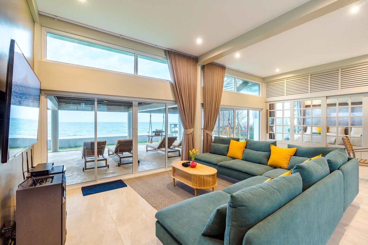 Living room with ocean view at Beach Vibe-Two V Pool Villa, ติดทะเล ใกล้หาดบางเกตุ ชะอำ. Large sectional sofa and sliding gla