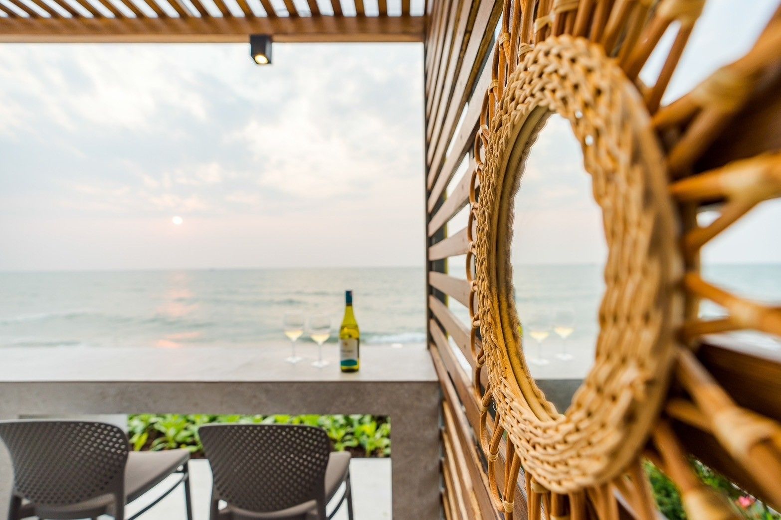 Beach Vibe-Two V Pool Villa beachfront terrace with wine glasses overlooking the ocean in Cha Am, Thailand.