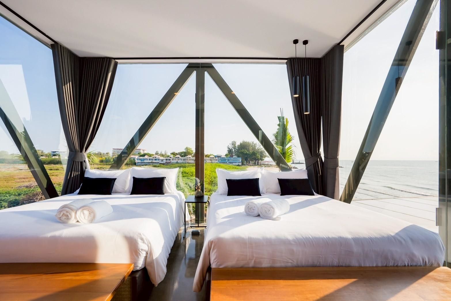 Twin beds with ocean view at Beyond V Pool Villa, หาดปึกเตียน-ชะอำ. Modern bedroom with floor to ceiling windows.