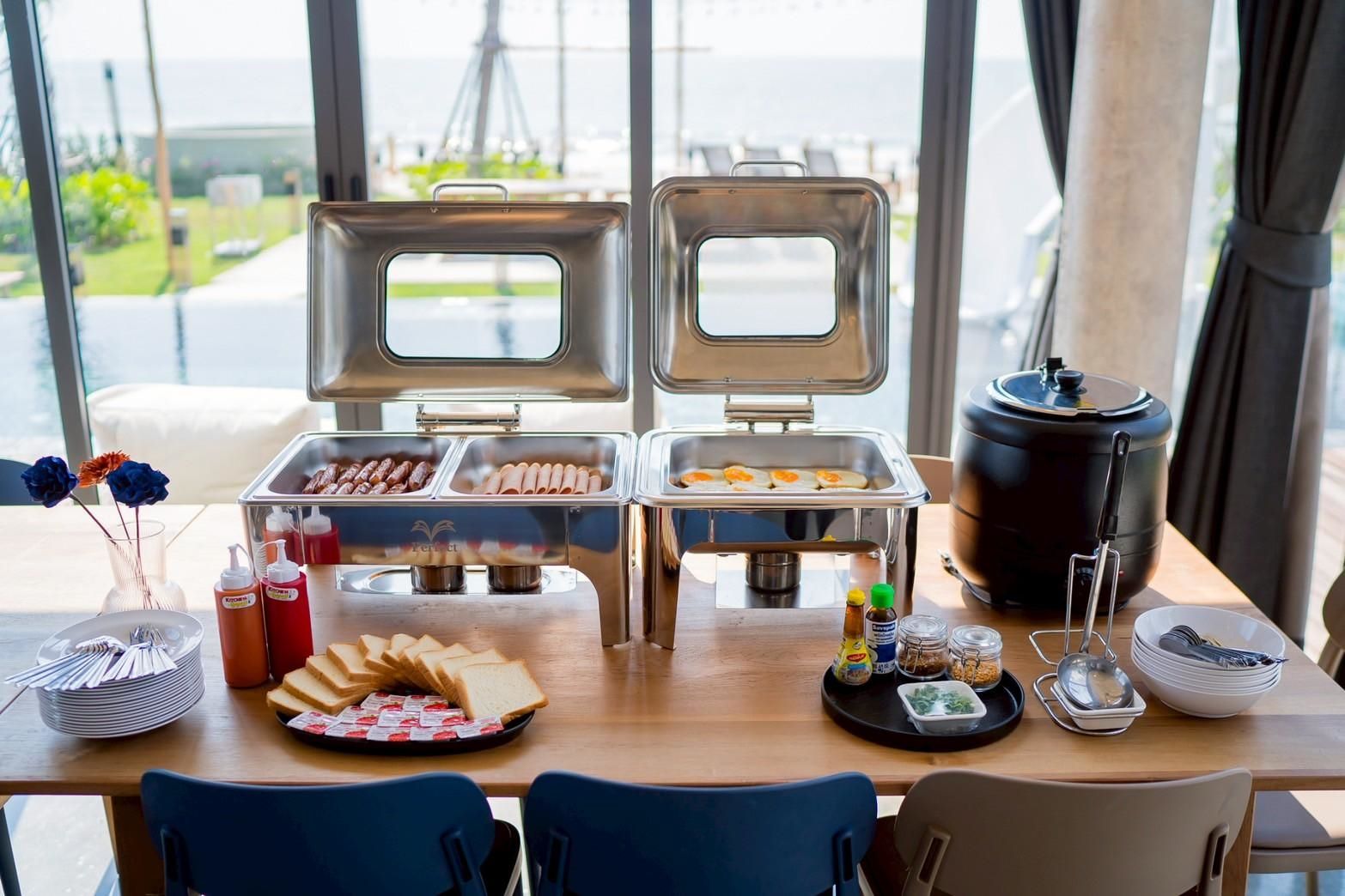 Breakfast buffet setup at Beyond V Pool Villa, หาดปึกเตียน-ชะอำ. View of the pool and ocean in the background.