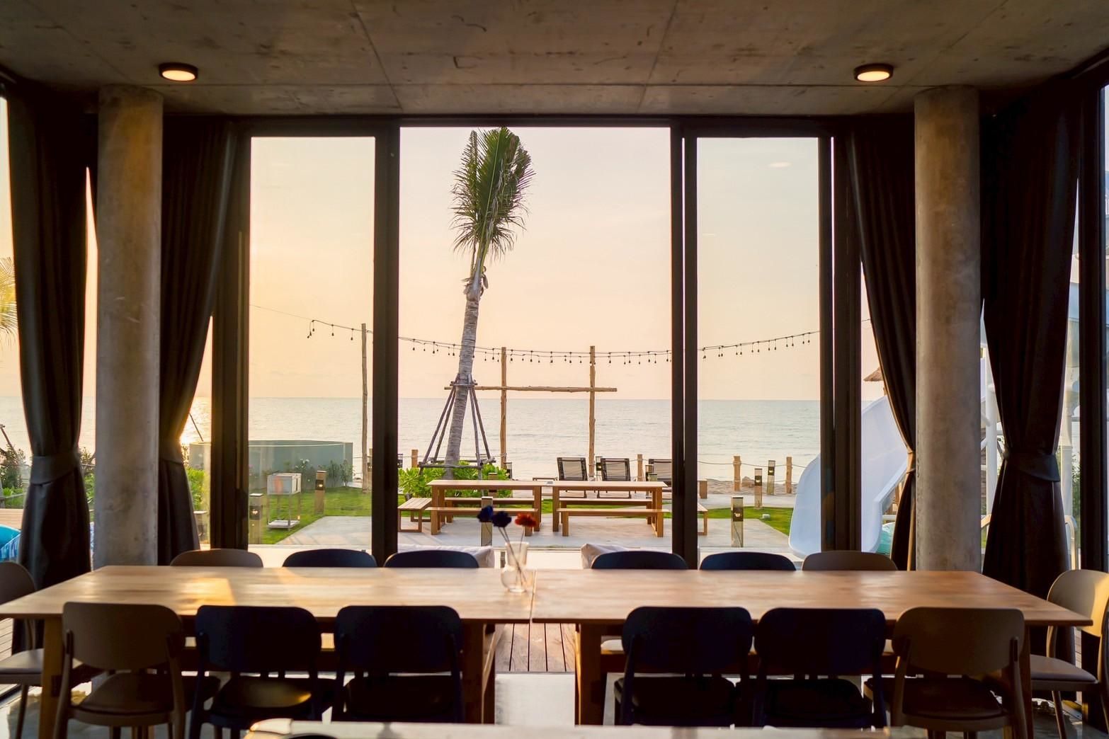Ocean view from the dining table at Beyond V Pool Villa, หาดปึกเตียน-ชะอำ. Large windows overlook the beach.