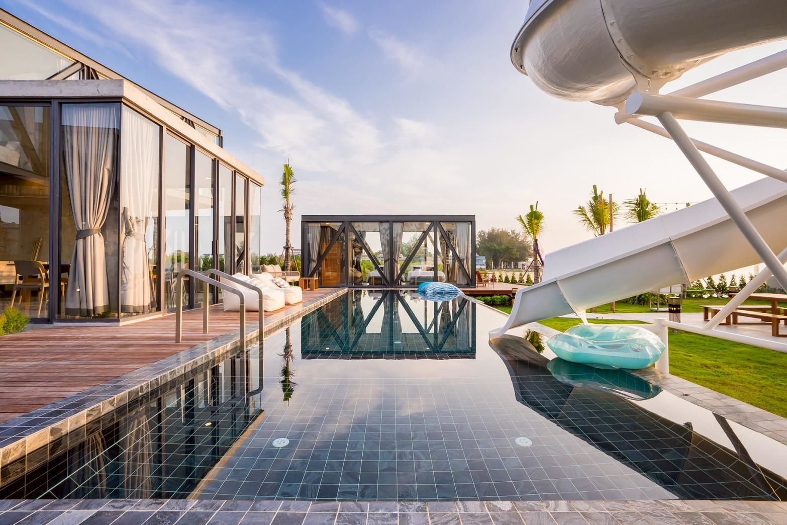 Beyond V Pool Villa pool with waterslide and reflections in หาดปึกเตียน-ชะอำ. Modern pool villa with outdoor lounge.