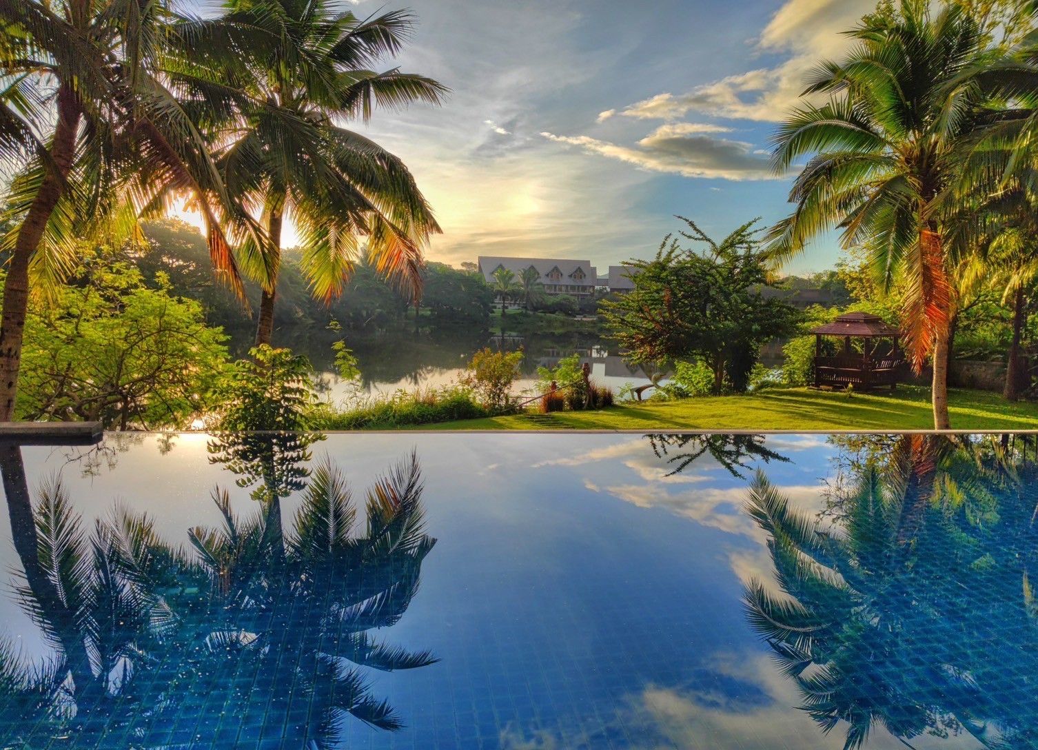 Infinity pool at sunset with palm tree reflections at Cabin Pool Villa Khao Yai.