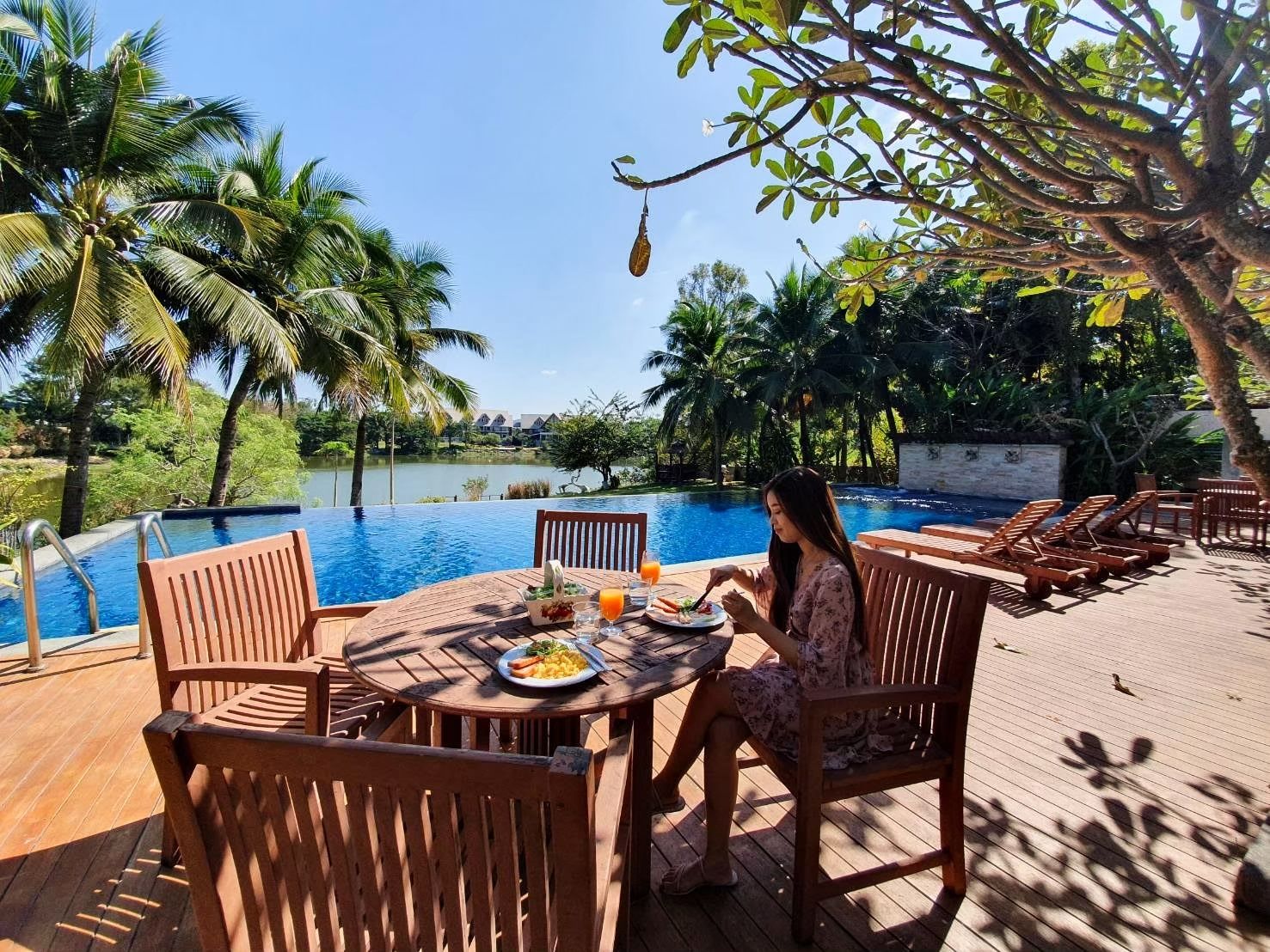 Poolside breakfast dining with lake and palm tree views at Cabin Pool Villa Khao Yai.