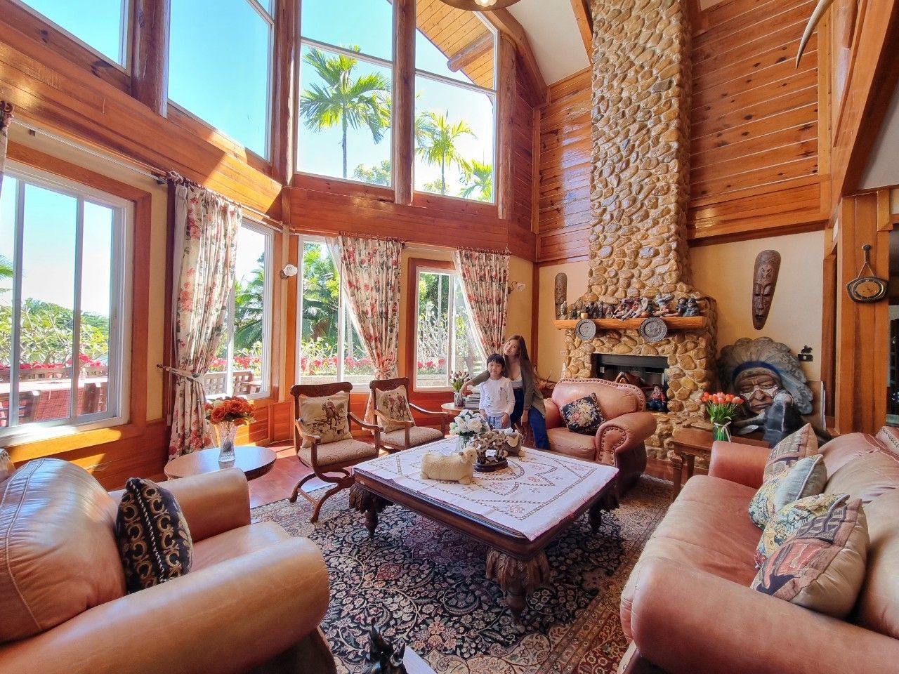 Living room with stone fireplace and double-height windows.