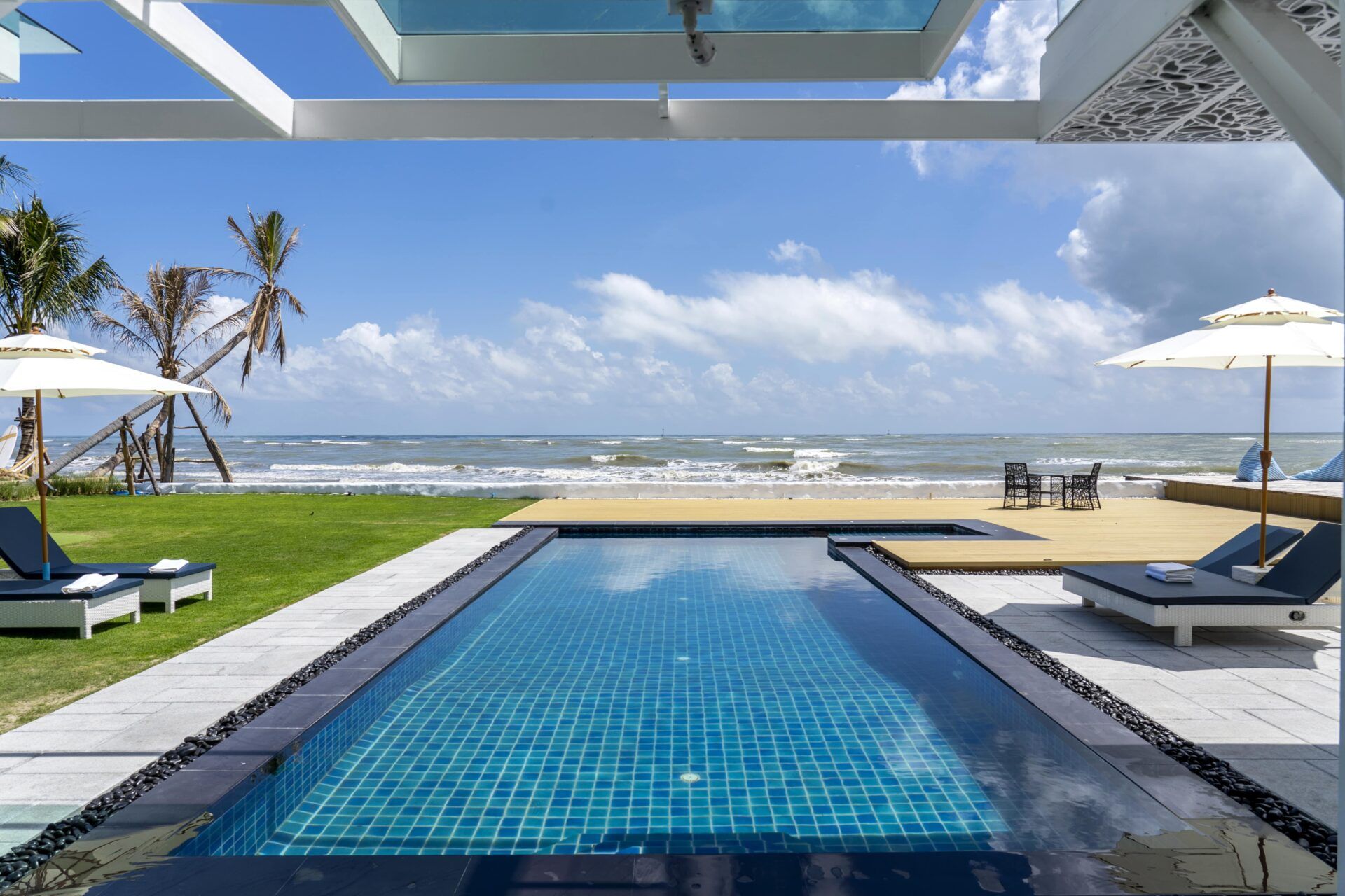Caribbean V Pool Villa beachfront pool and deck in Sam Roi Yot, Pranburi. Ocean view with lounge chairs and dining table.