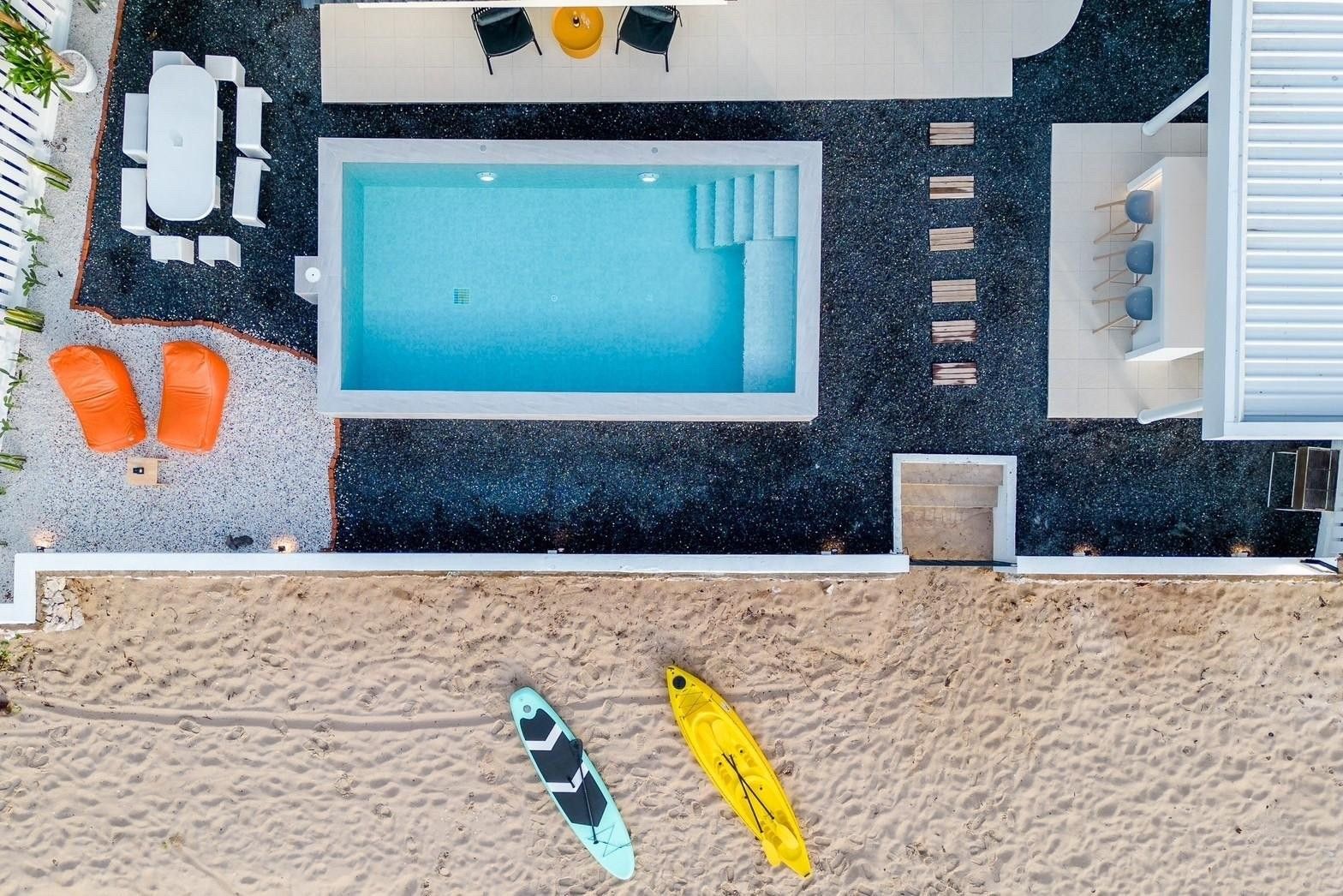 Aerial view of Costa IV Beachfront Pool Villa, ชะอำ เพชรบุรี, with pool, patio, and beach access with kayaks.