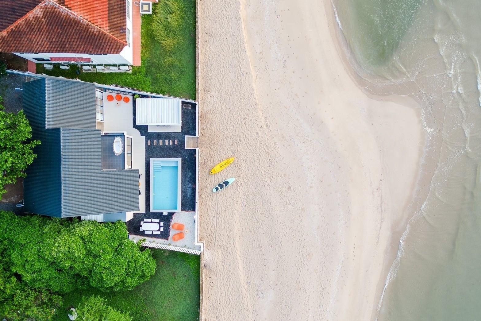 Aerial view of Costa IV Beachfront Pool Villa, Cha-am. Beachfront location with pool, patio, and kayaks on the sand.
