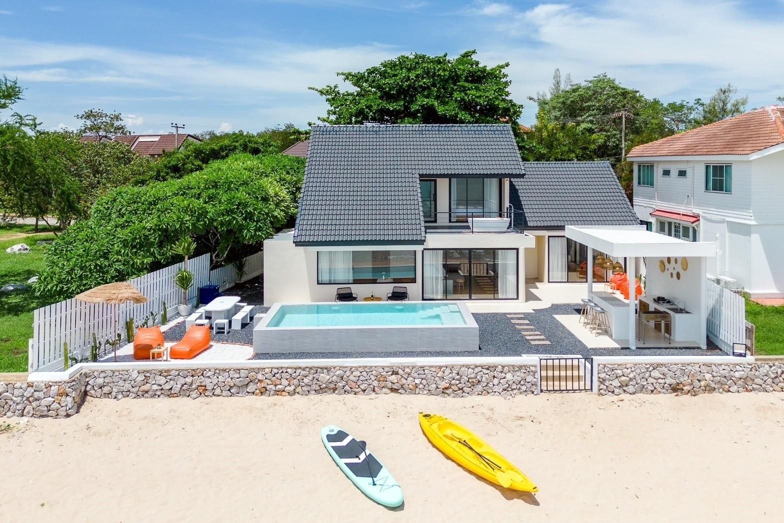 Aerial view of Costa IV Beachfront Pool Villa, ชะอำ เพชรบุรี. Kayak and paddleboard on the beach in front of the villa.