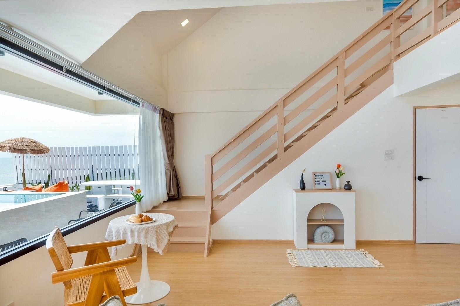 Indoor staircase and table at Costa IV Beachfront Pool Villa, Cha-am, Phetchaburi. View of pool and ocean.