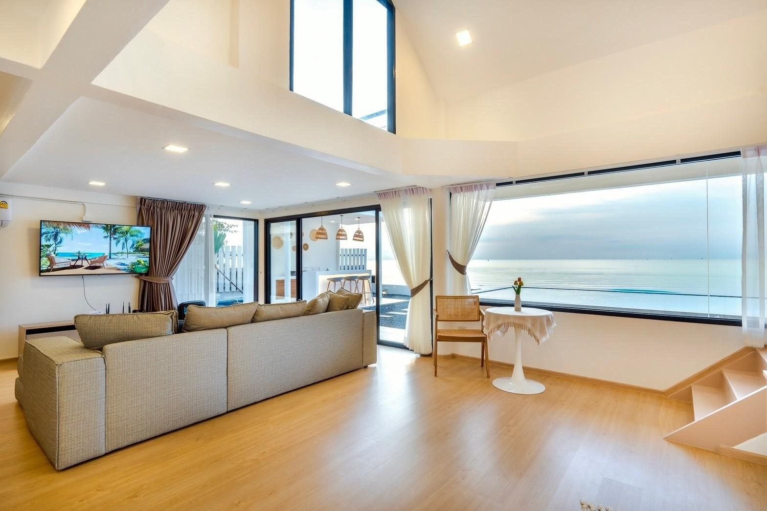 Living room with ocean view at Costa IV Beachfront Pool Villa, Cha-am, Phetchaburi. Sofa, TV, and large windows.