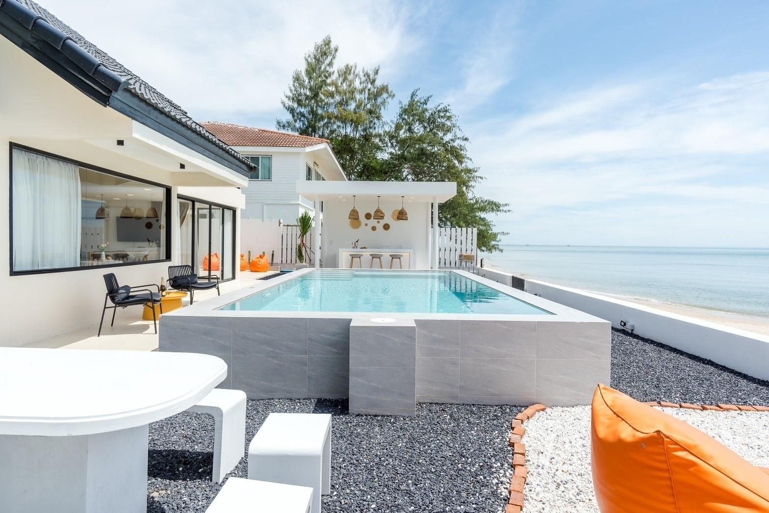 Costa IV Beachfront Pool Villa in ชะอำ เพชรบุรี features a pool with a bar overlooking the ocean. Outdoor seating and beanbag