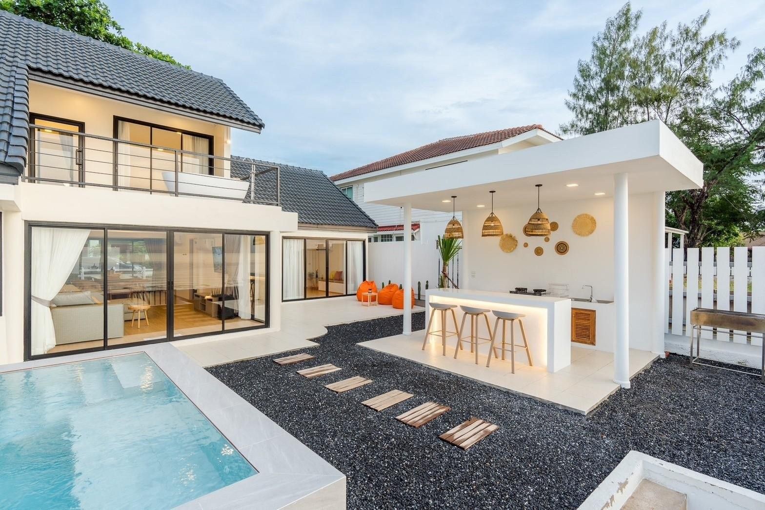 Costa IV Beachfront Pool Villa in ชะอำ เพชรบุรี features a poolside bar with stools and a black gravel walkway.