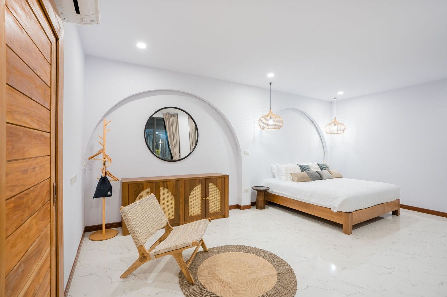 Cross Sea VII Pool Villa bedroom in หาดคลองเทียน-ชะอำ features a king bed, round mirror, and woven chair on a round rug.