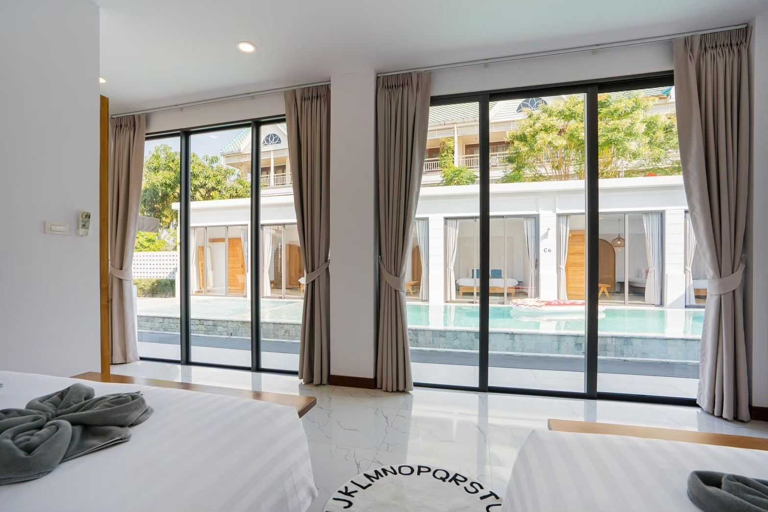 Bedroom view at Cross Sea VII Pool Villa, หาดคลองเทียน-ชะอำ. Large windows overlook the pool and adjacent villas.