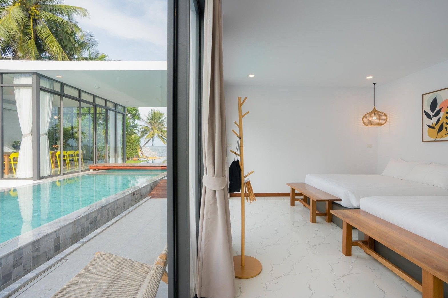 Twin beds with pool view at Cross Sea VII Pool Villa, หาดคลองเทียน-ชะอำ. Modern bedroom with wooden benches.