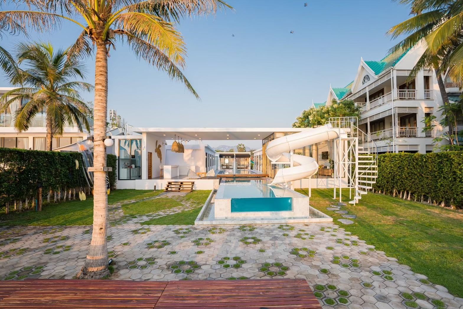 Cross Sea VII Pool Villa in หาดคลองเทียน-ชะอำ features a pool with a water slide. View of the villa from the pool deck.
