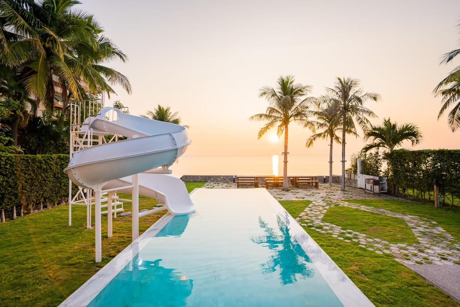 Cross Sea VII Pool Villa pool with water slide at sunset, หาดคลองเทียน-ชะอำ. Palm trees and ocean view.