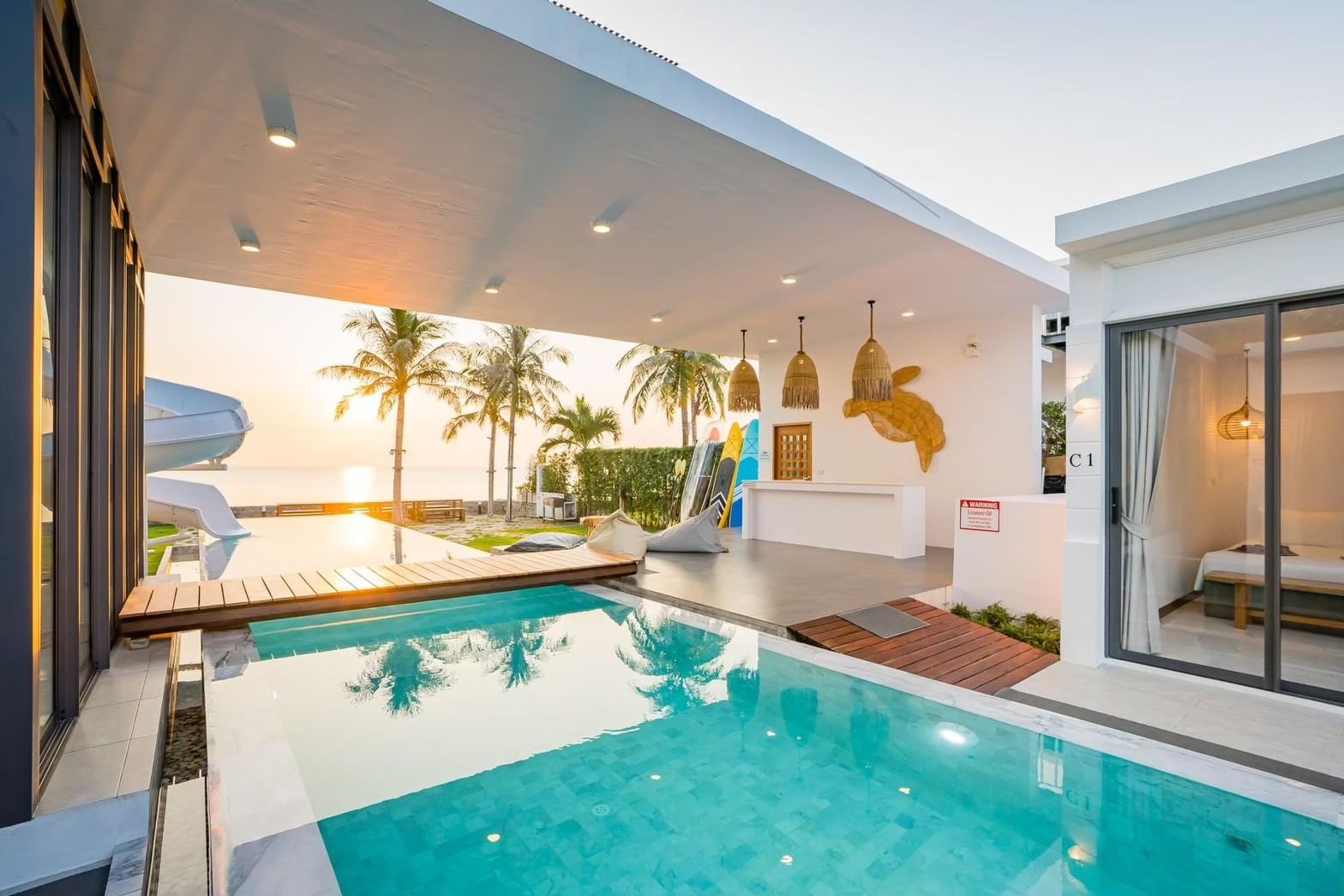 Cross Sea VII pool villa in หาดคลองเทียน-ชะอำ features a pool with water slide, outdoor bar, and ocean view at sunset.