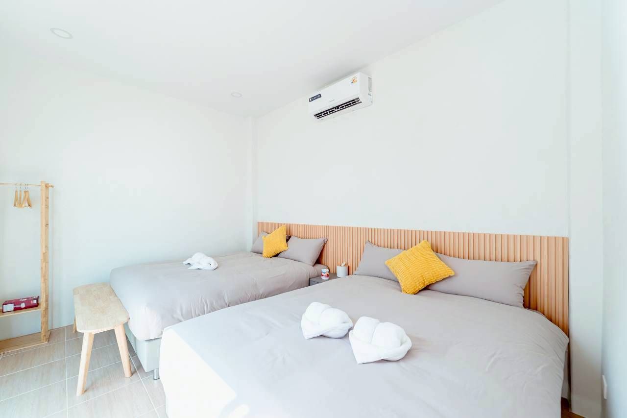 Darlington IV Pool Villa bedroom with two twin beds, yellow pillows, and wooden headboards.
