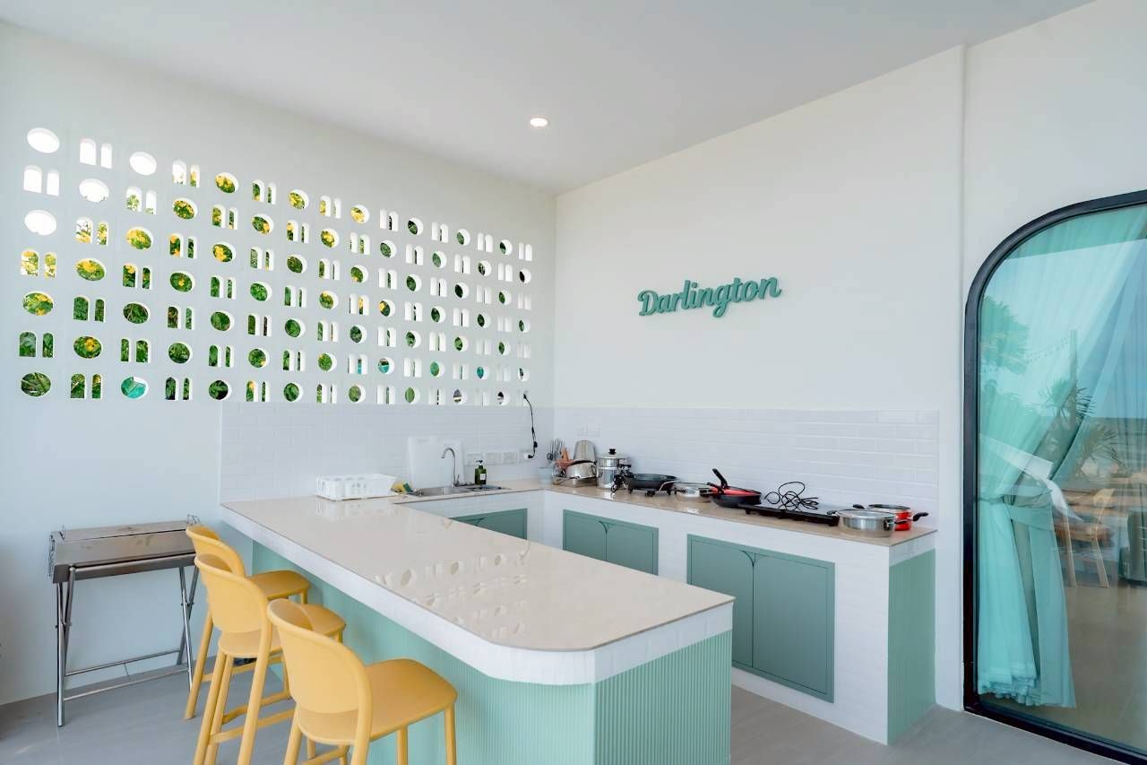 Darlington IV pool villa kitchen with breakfast bar and yellow stools. Unique architectural wall design lets in natural light