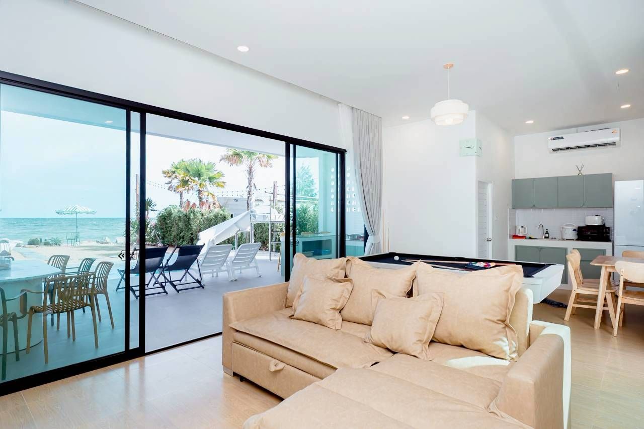 Darlington IV Pool Villa living room with sofa, pool table, and ocean view through sliding glass doors.