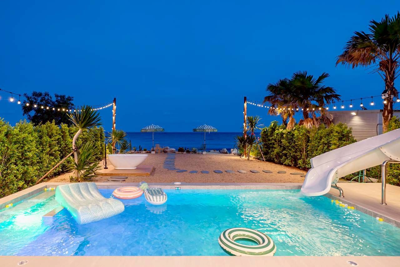 Darlington IV pool villa beachfront pool with water slide and ocean view at night.