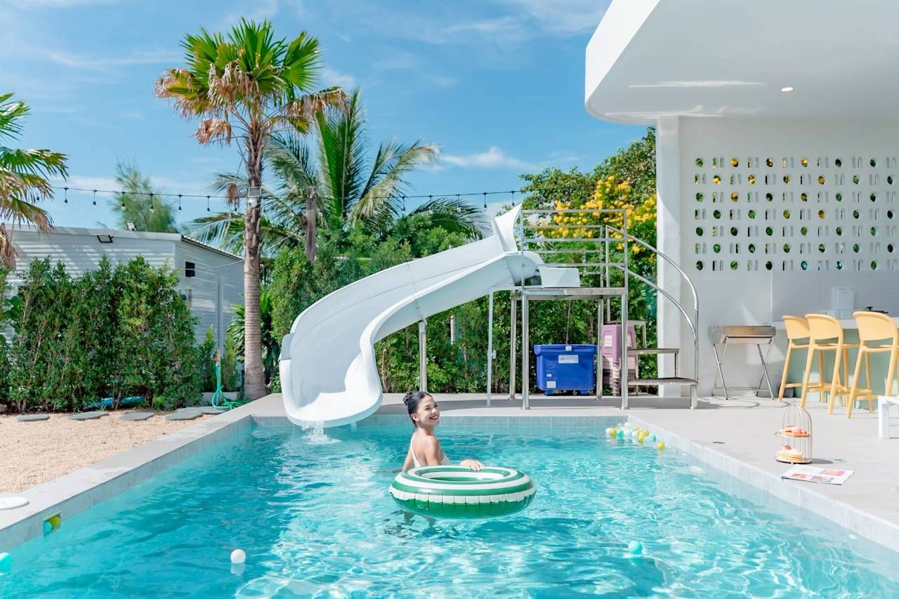 Darlington IV pool villa with water slide. Woman in inflatable ring enjoying the pool in Thailand.