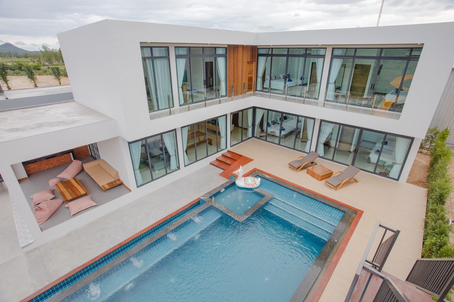 Aerial view of Exclusive Proud VI Villa, Hua Hin. Modern architecture, pool, and outdoor lounge area visible.