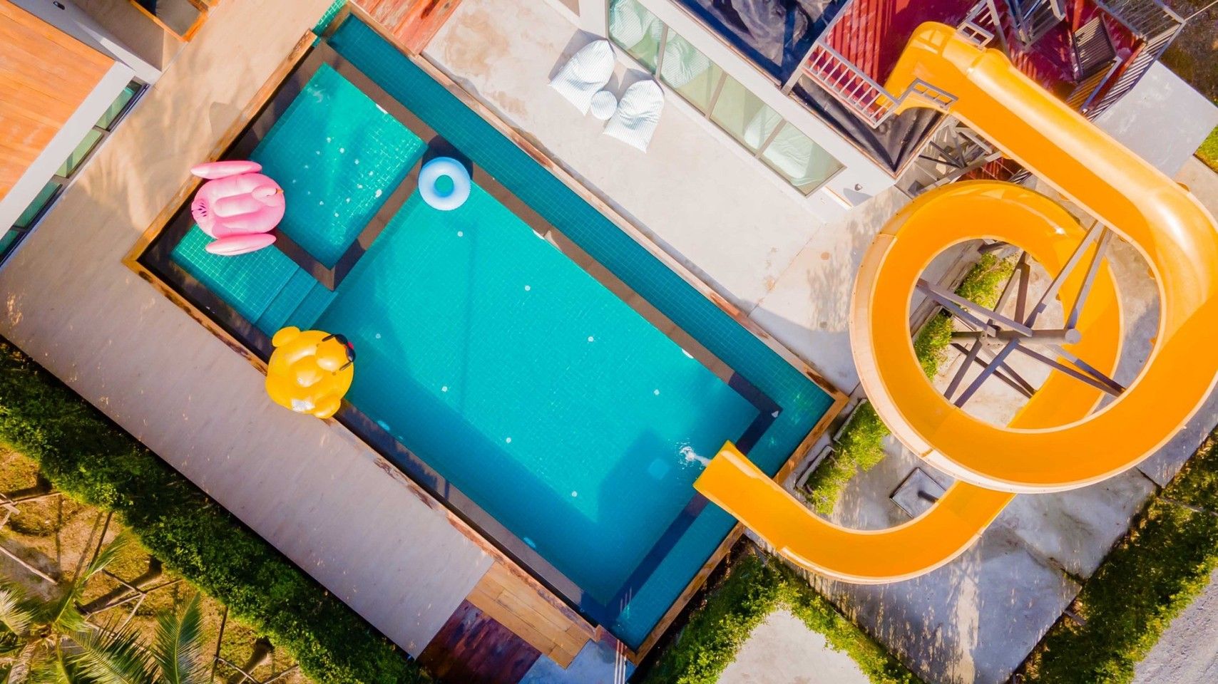 Aerial view of Exclusive Proud VII Villa pool in Hua Hin with waterslide and inflatable toys.