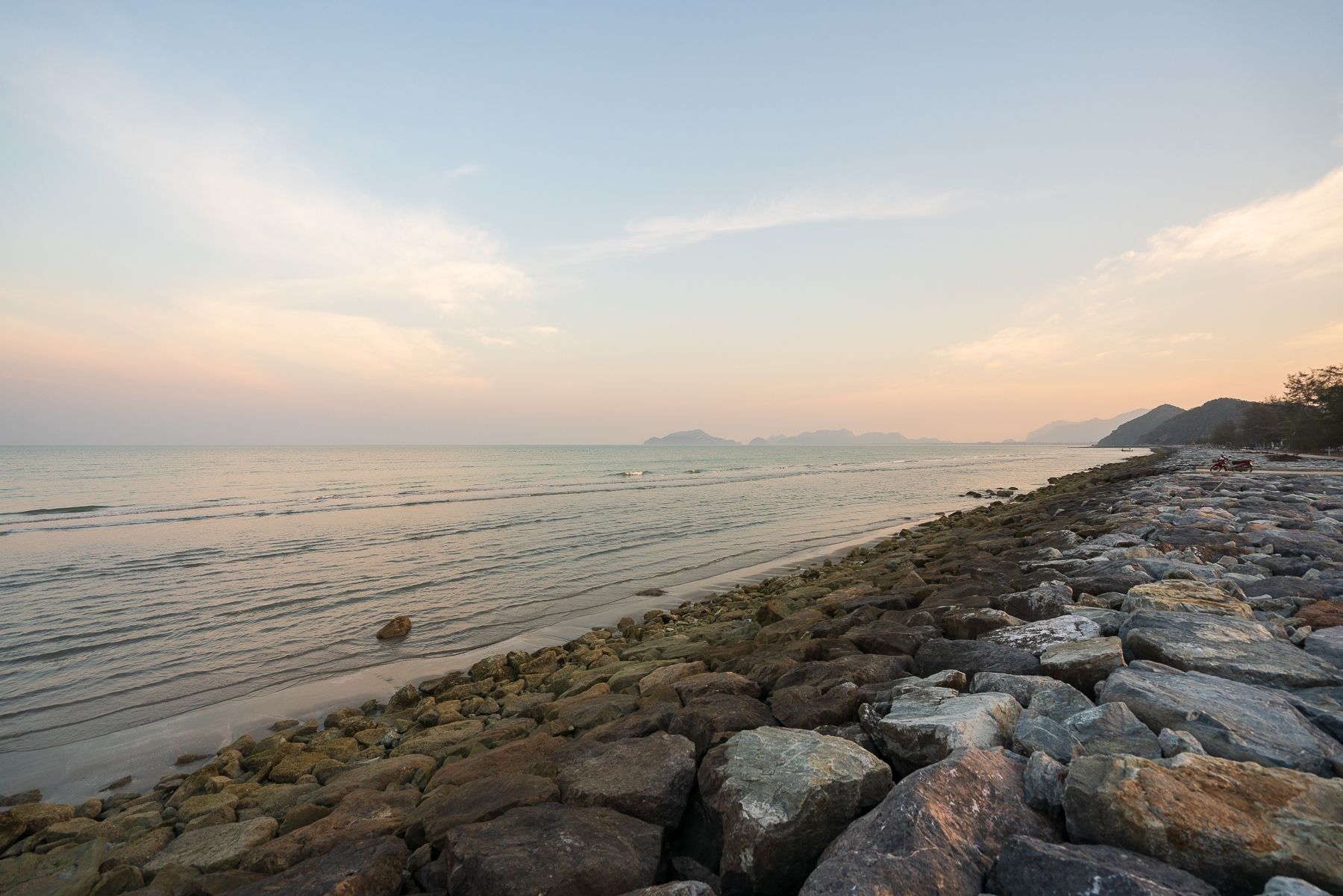 Beachfront view near G Villa III Pool Villa, Pak Nam Pran, Pranburi. Rocks line the shore at sunset.