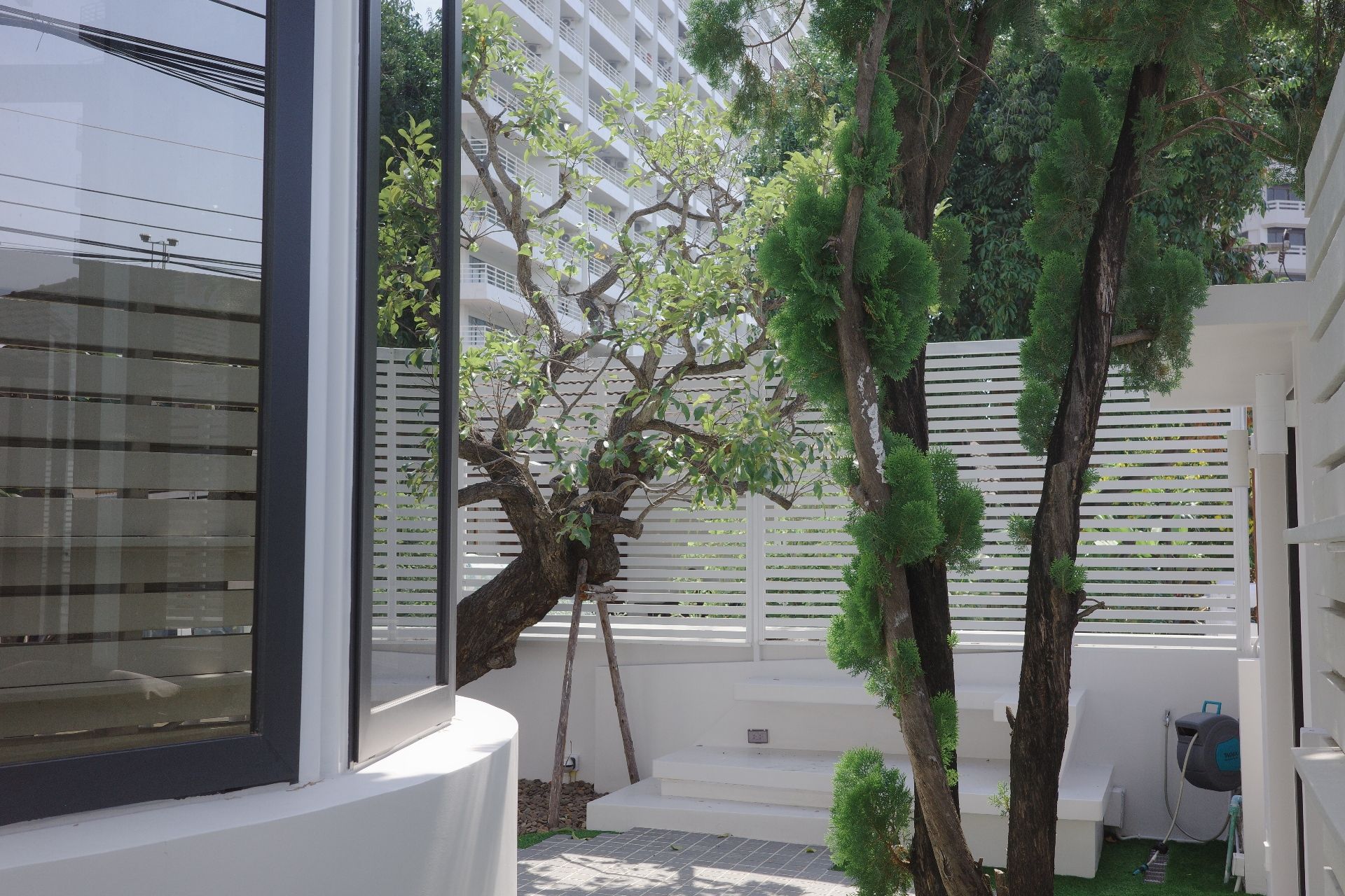 Garden view with trees and white fence at Glass Beach III Pool Villa, Dongtan Beach, South Pattaya.
