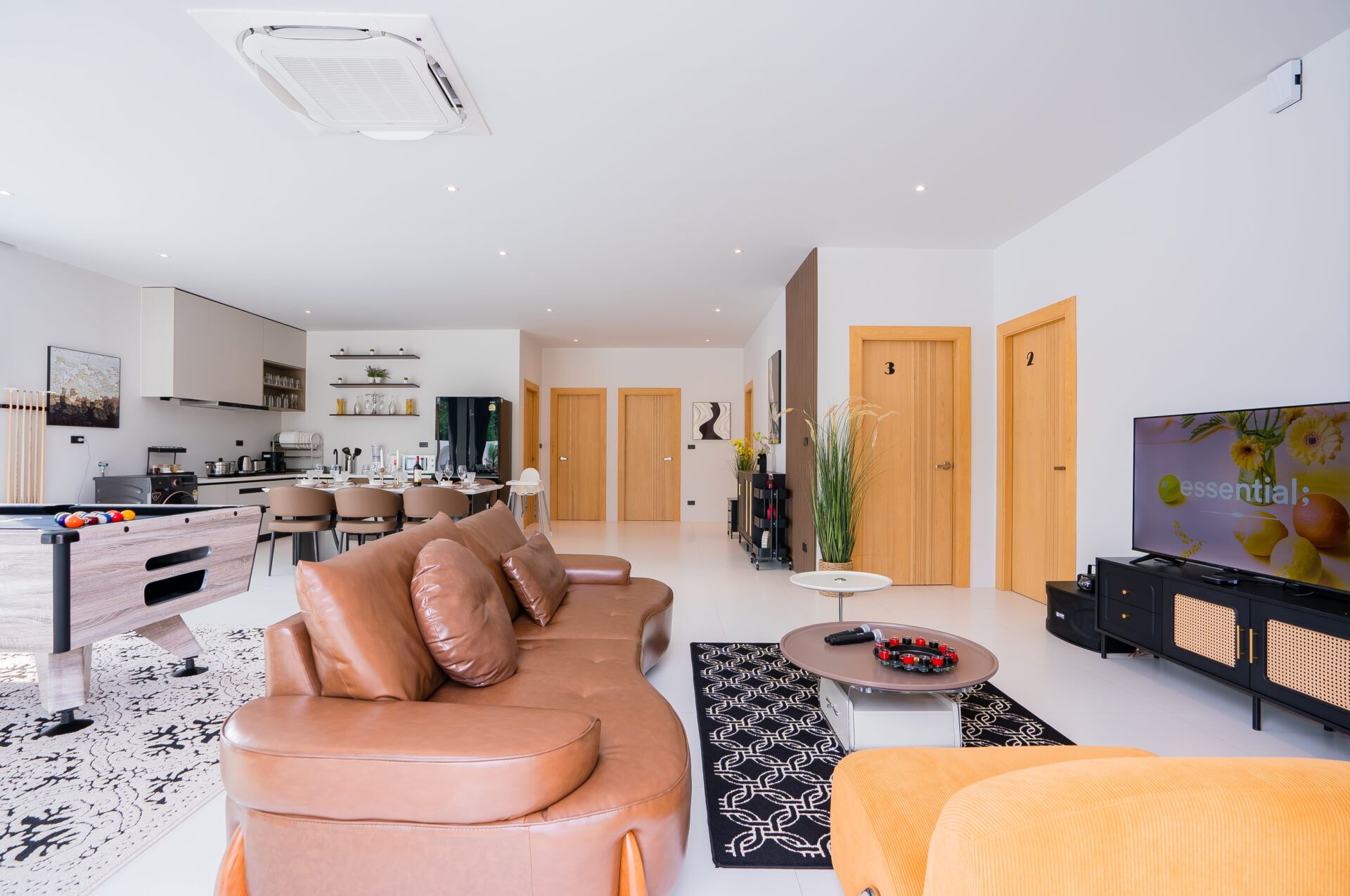 Open-plan living area at Good Day V Pool Villa, South Pattaya. Features a leather sofa, pool table, and kitchen-dining area.