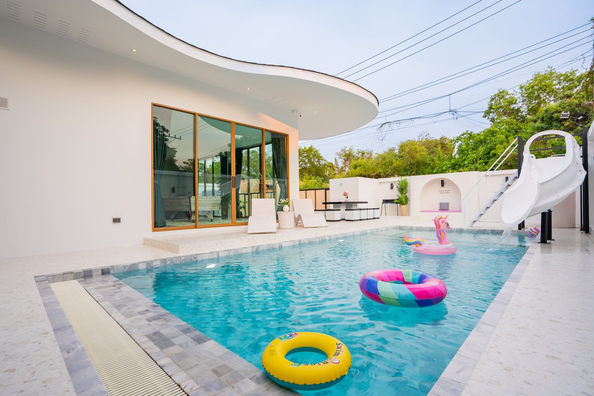 Good Day V Pool Villa in Jomtien features a private pool with a water slide and colorful inflatable toys.