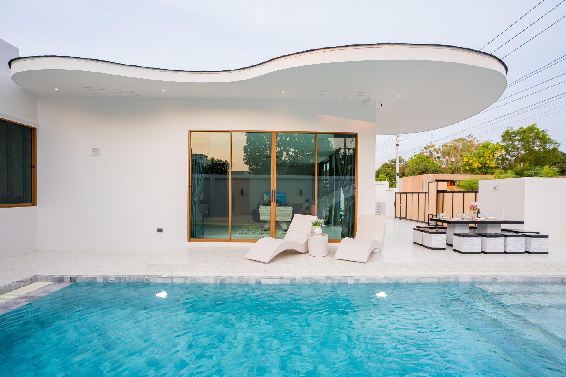Good Day V Pool Villa in Jomtien. View of the pool, lounge chairs, and outdoor dining area on the pool deck.