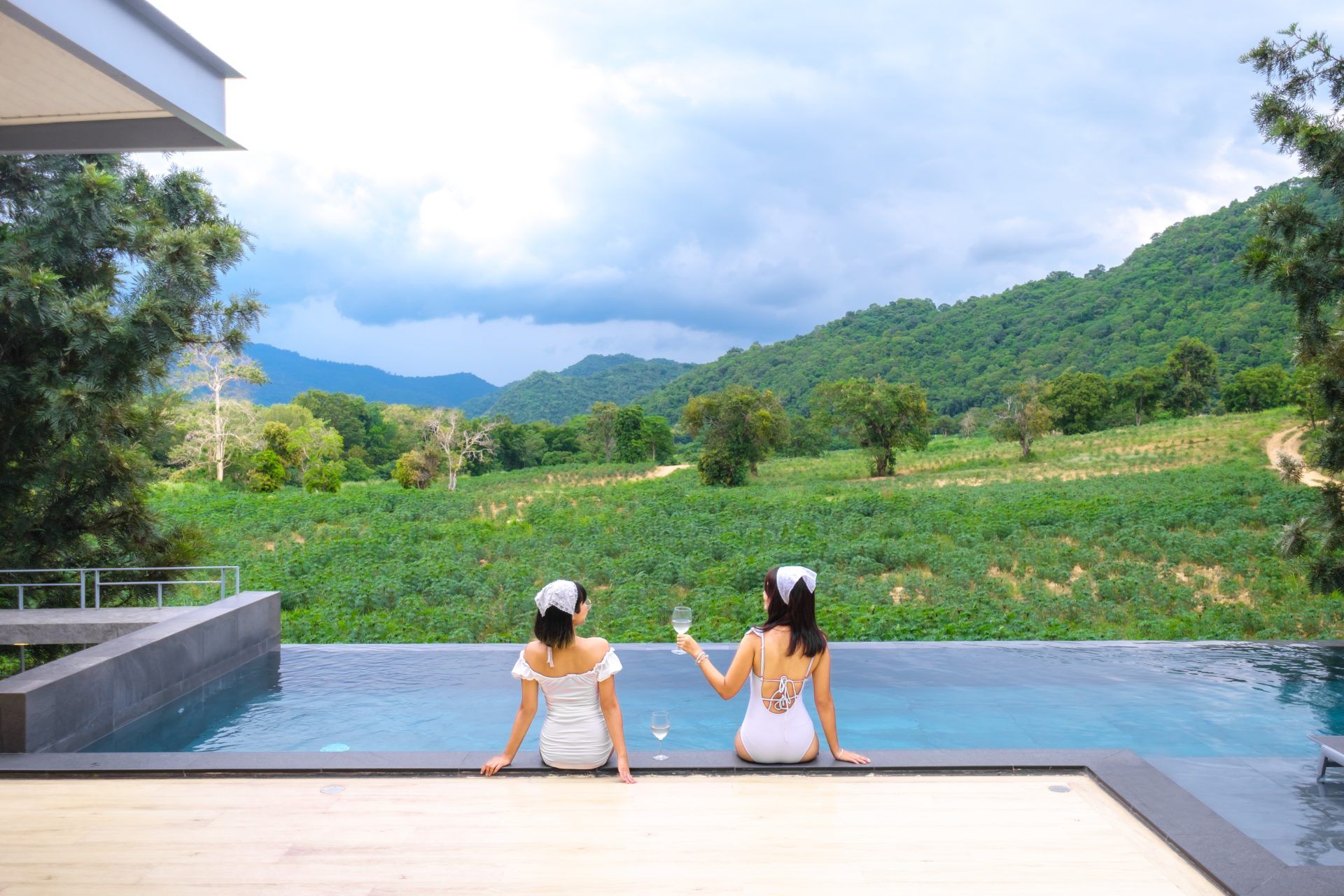 Two women enjoy the infinity pool with mountain views at Kin Khaoyai V Pool Villa, หมูสี เขาใหญ่.