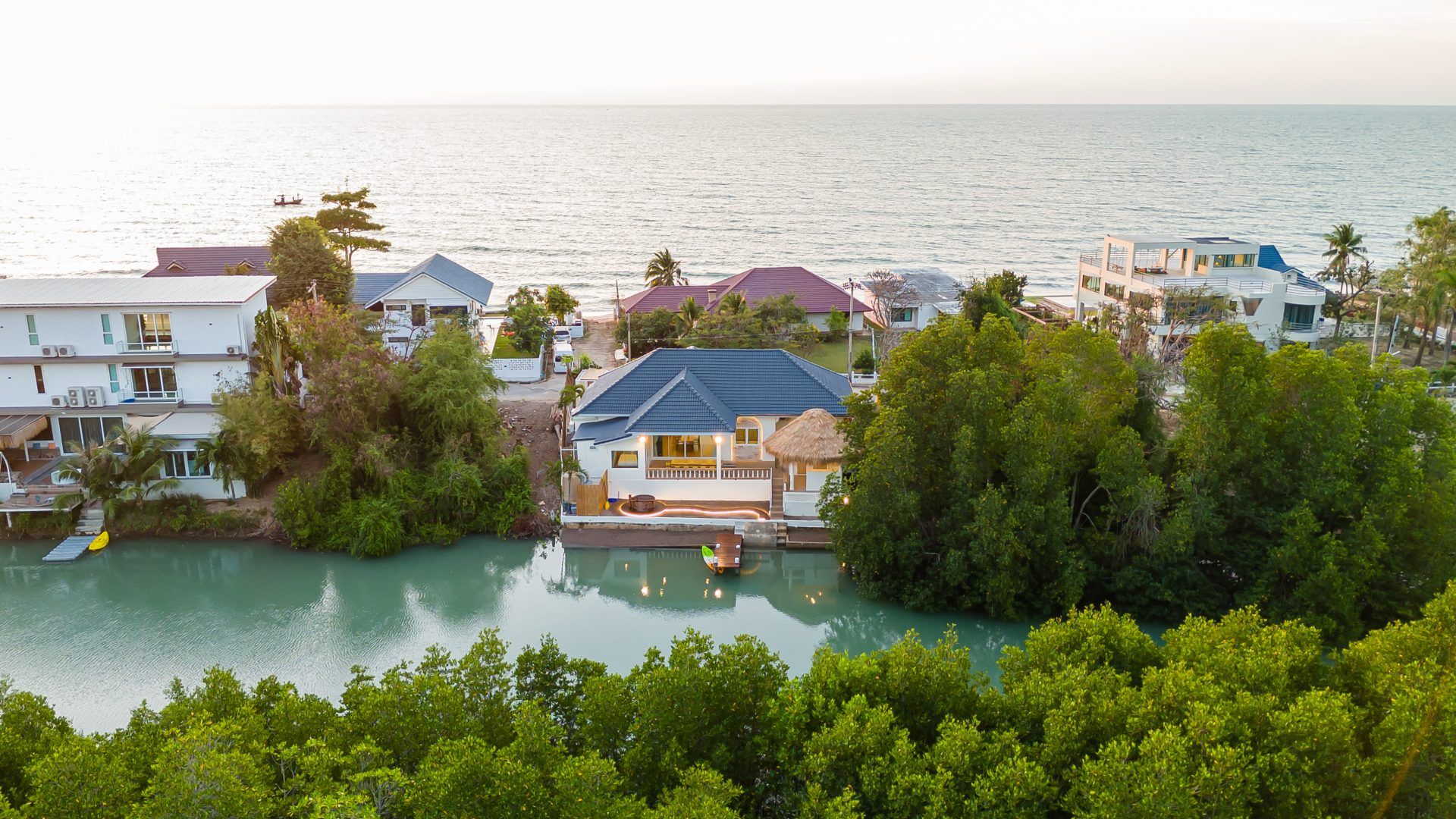 Aerial view of Lagoon Beach V Pool Villa, ใกล้หาดบางเก่า-ชะอำ. Waterfront villa with dock, surrounded by trees.